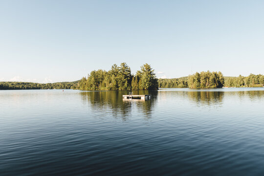 Landscape view of a lake with a floating pier on the water in front of trees