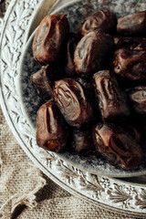 dried dates on vintage oriental old metal plate with an ornament. traditional oriental sweets. healthy natural snack. selective focus