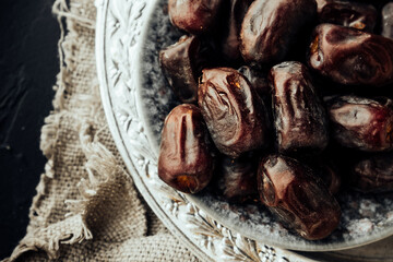 dried dates on vintage oriental old metal plate with an ornament.traditional iftar evening snack, oriental sweets. healthy natural snack. selective focus