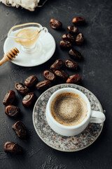 freshly brewed coffee with foam, dried dates on vintage dishes oriental in dark atmosphere. oriental sweets, honey honey stick. oriental holiday layout, vertical, selective focus