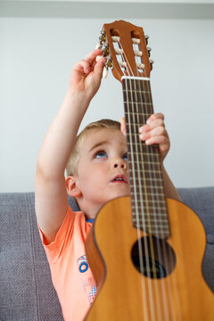 Boy is tuning a small guitar
