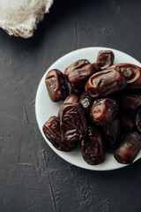 traditional iftar evening snack in the fast of Ramadan. dried dates on farvor plate on dark background top view. traditional oriental sweets. healthy natural snack. vertical, selective focus