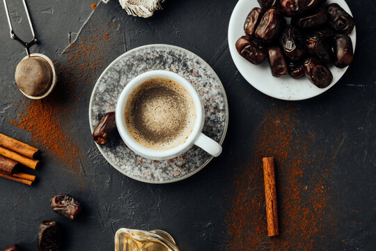 oriental meal. freshly brewed coffee, dried dates, cinnamon sticks, honey, spilled coffee and spices, burlap cloth on dark background. colorful image national food and drink. top view, selective focus