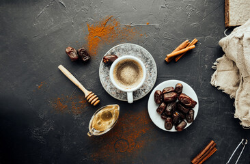 oriental meal. freshly brewed coffee, dried dates, cinnamon sticks, honey, spilled coffee and spices, burlap cloth on dark background. colorful image national food and drink. top view, selective focus