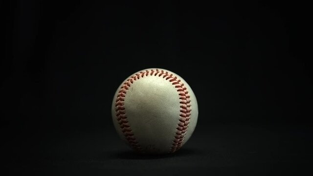 Baseball is picked up by a man's hand. Black Background
