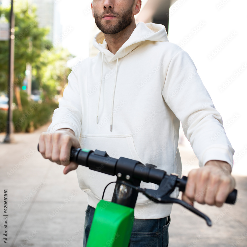 Wall mural Man with hoodie rining an electric scooter