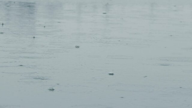 Lake surface in the rain with rain drops. 4K 120fps slow motion.