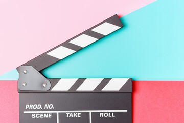 Fototapeta na wymiar The clapper board on pink, red and blue background close-up.