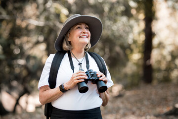 Active old woman using binoculars to see the beauty of nature