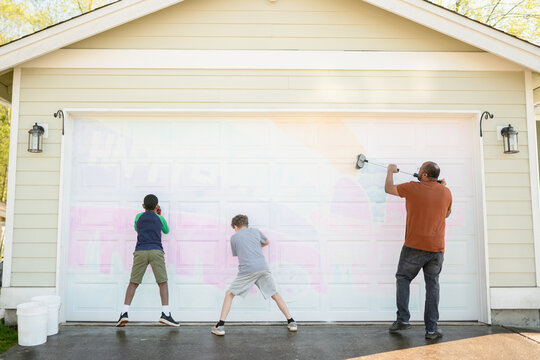Black father and sons clean garage door mural