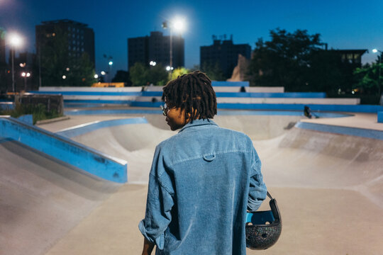 Young African American woman holding a protective head gear at the skate park