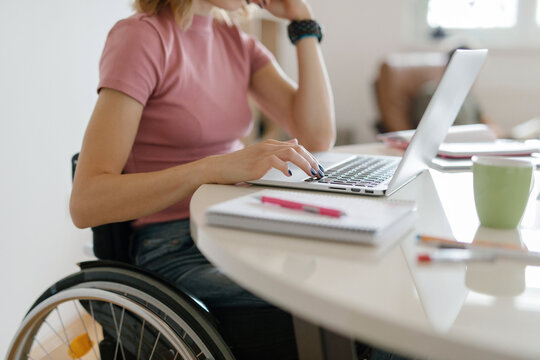 Young woman in a wheelchair working from home on her laptop
