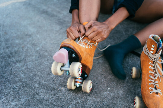 Unrecognizable African American woman tying shoe laces on her rollerskate