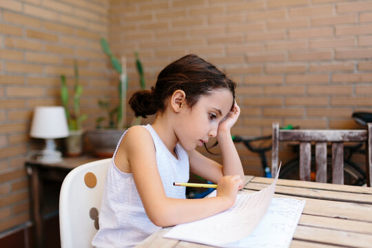 Kid focus on doing homework in her home outdoor terrace