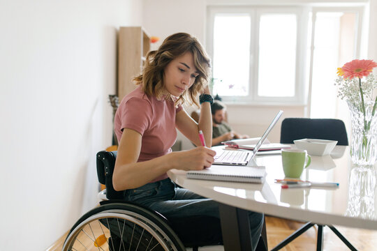 Young woman in a wheelchair working from home on her laptop