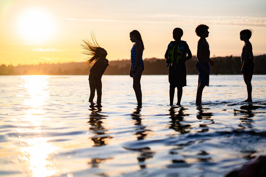 Silhouette of girl flipping hair in ocean with friends