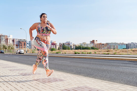 Full-figured woman running along a sidewalk