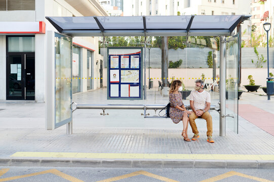 Mature couple wearing face masks at a bus stop