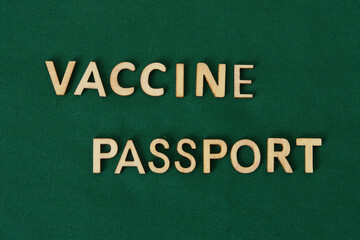 Obraz premium COVID vaccine passport wooden alphabet letters on a green fabric. Green Passport.