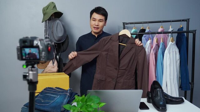 young man selling clothes and accessories online by camera live streaming, business online e-commerce at home