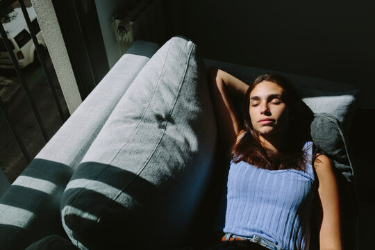 Young woman taking a siesta on the couch next to a window