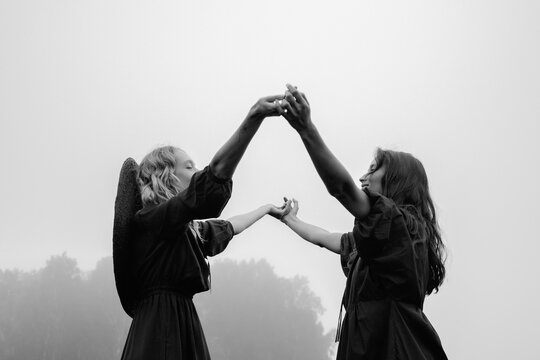two beautiful girls in black dresses posing dancing in a wheat field