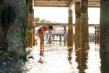 Girl wading in water under dock