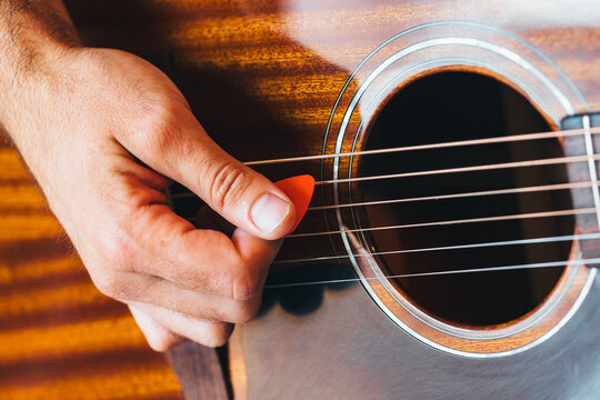 Close-up shot of anonymous musician's hand playing guitar with a pick