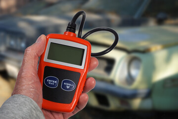 Mechanic holding code reader to diagnose car engine problems 