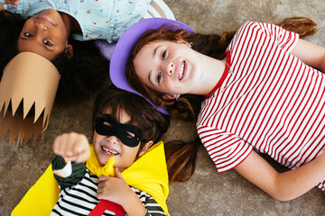 Happy multiethnic friends in Halloween costumes on floor