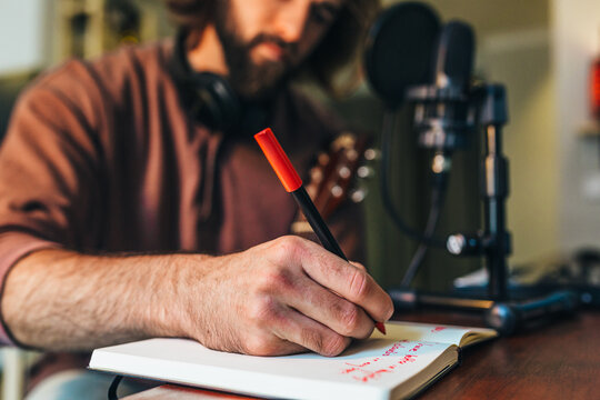 Young man writing song lyrics at home music studio