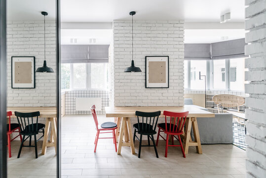 Kitchen area in a minimalist apartment with colourful chairs and white brick wall