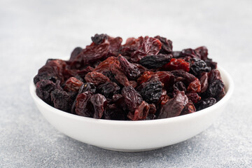 Dried raisins from dark grapes in a plate on a gray concrete background, copy space. top view