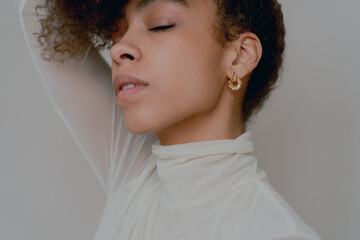 Woman With Afro Wearing White Turtle Neck In Front Of White Backdrop
