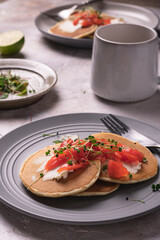 Morning breakfast with pancakes with salmon and micro greens on a gray plate