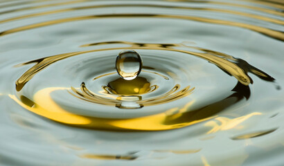 Water drops frozen at high speed in golden pool of water showing surface tension and droplet...