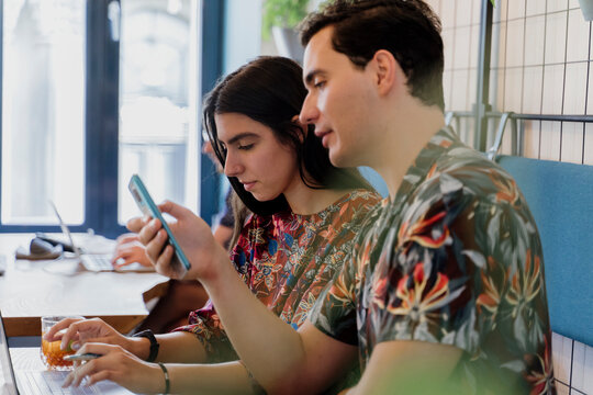 Young happy couple having brunch and working studying in nice cafeteria