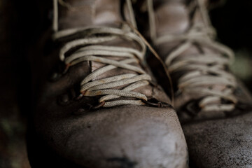 closeup of Vintage used hiking boots hanging from tree in forest