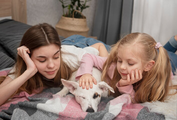 Teenage girl and child playing with their dog