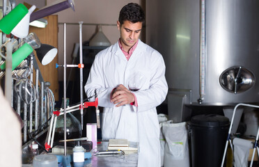 Male laboratory technician working with wine in cellar