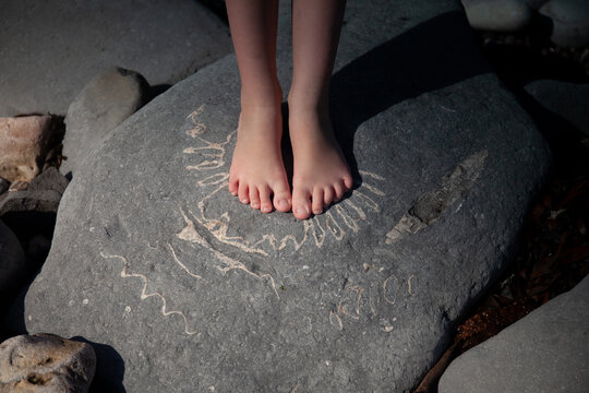 Child's feet on large ammonite fossil.