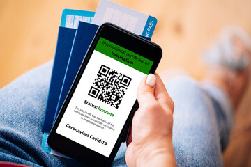The woman holding the mobile phone a mockup for digital vaccination certificate in one hand and...
