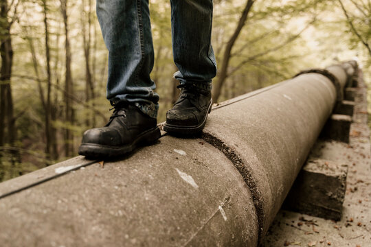 Closeup of boots walking on top of pipeline in forest