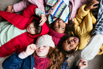 Funny diverse children in outerwear lying on floor