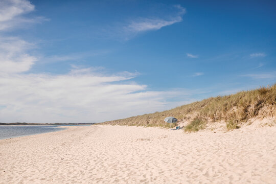 Sandy beach with parasol on sunny day
