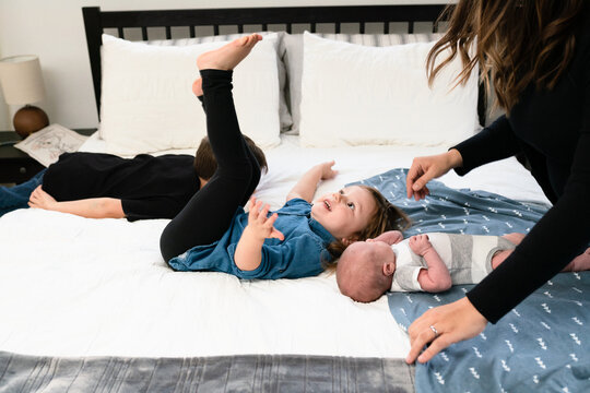 Toddler flails on bed next to newborn