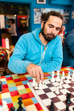 Adult playing chess in bar for leisure