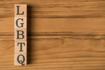 Top view photo of wooden cubes labeled LGBTQ on isolated wooden background with copyspace