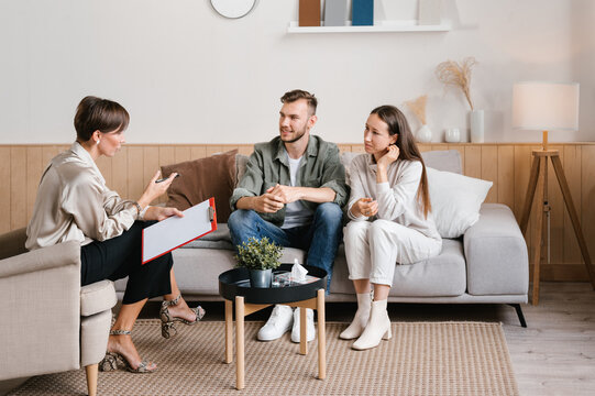 Young couple and female realtor talking in modern apartment