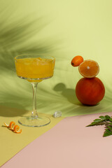 Refreshing Summer juice with ice,fresh orange,lemon and kumquat on green background with hard shadows of palm leaves on background.Balancing citrus fruits and refreshing cocktail.